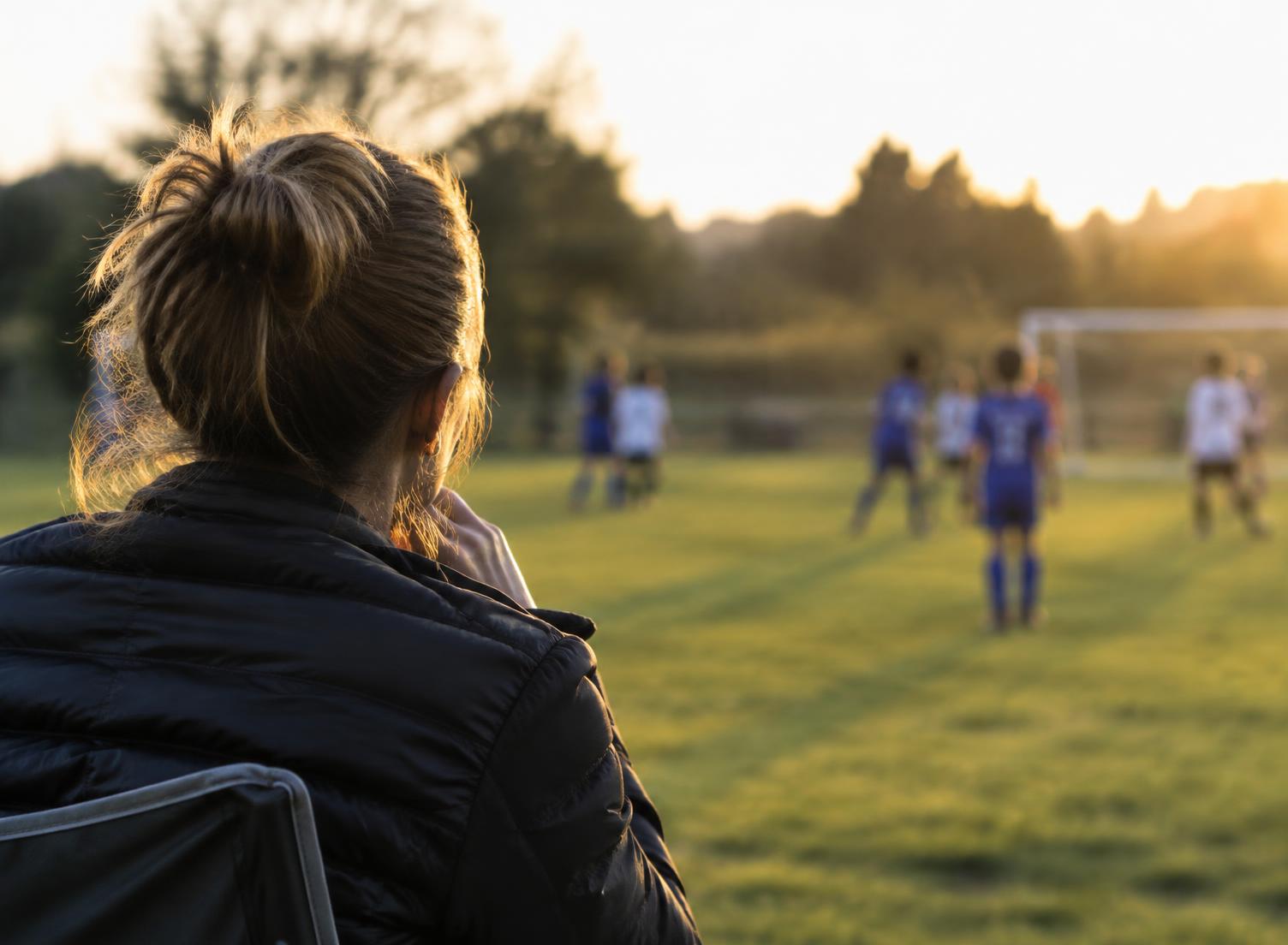 Parent watching a soccer game from the sideline